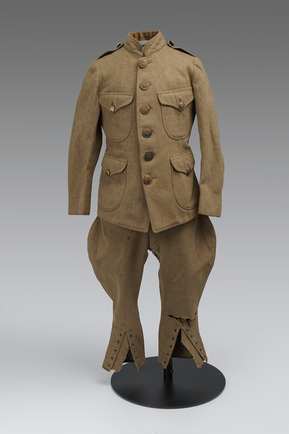 Modern photograph of a child-sized brown military uniform jacket and pants.