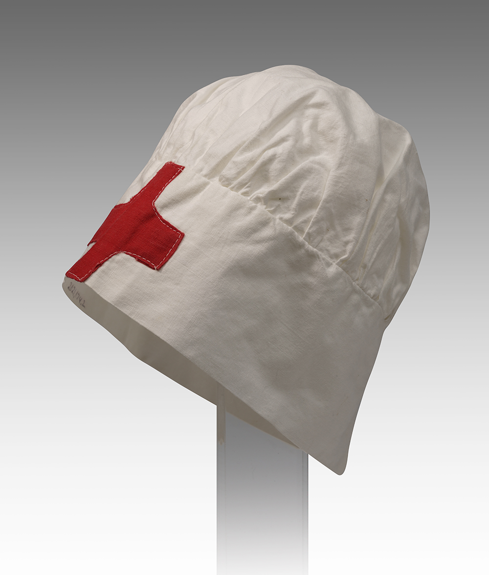 Modern photograph of a white bonnet-like cap with a red cross on the brim