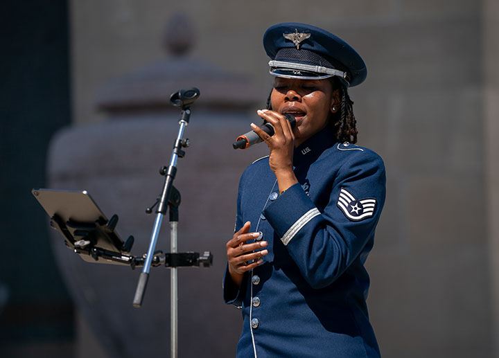 Modern photograph of a Black woman in military uniform singing into a microphone