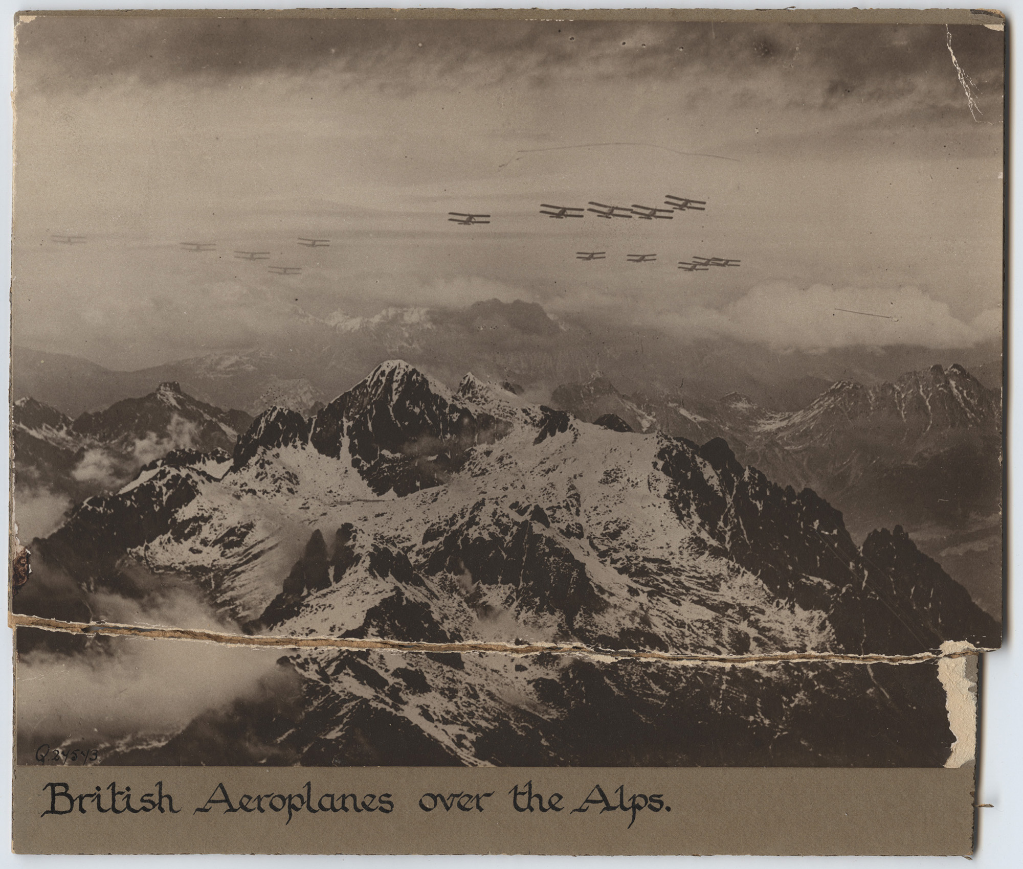 Photographie aérienne en noir et blanc d'une chaîne de montagnes enneigée avec des avions de la Première Guerre mondiale survolant les sommets