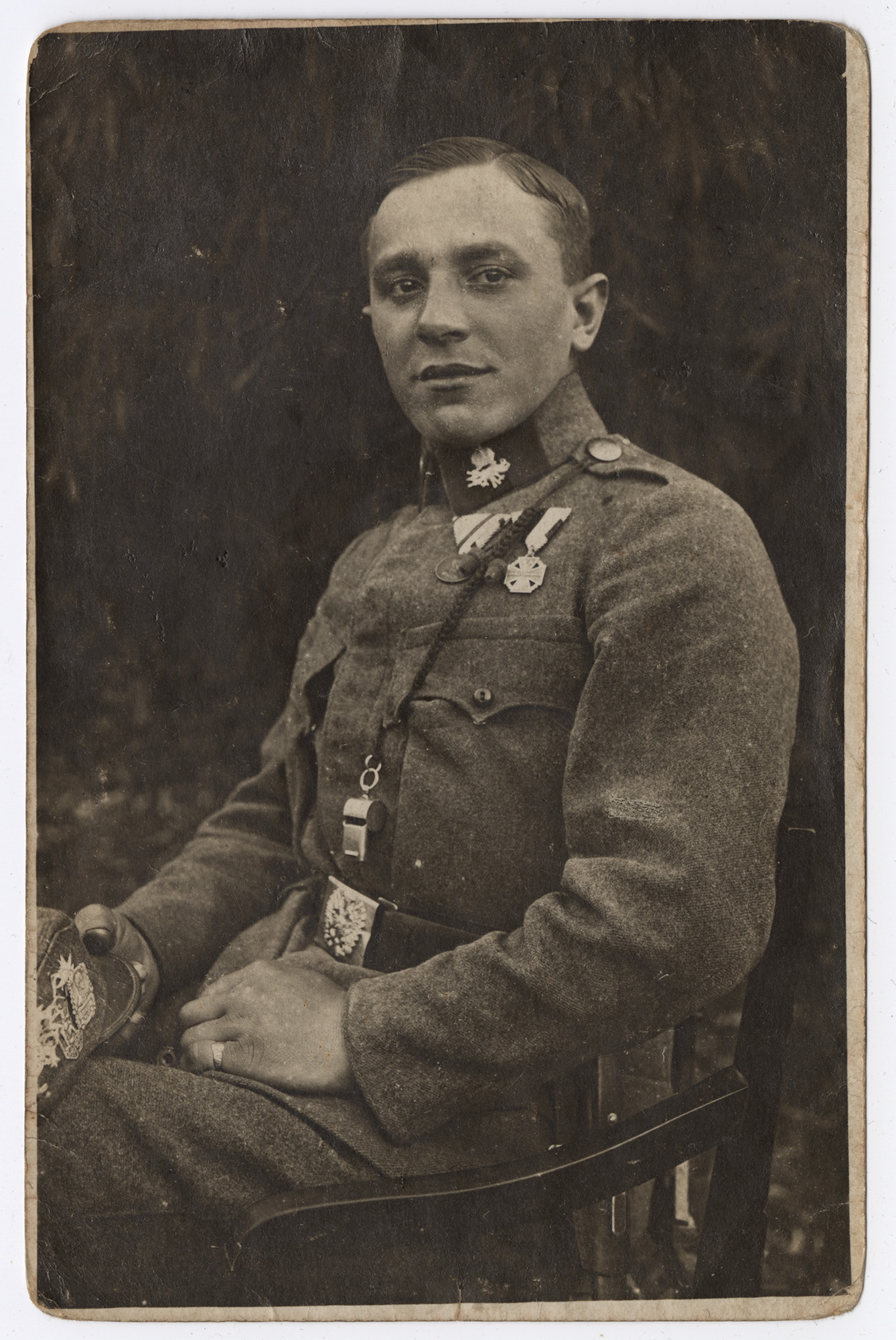 Photographie en noir et blanc d'un jeune homme blanc en uniforme militaire portant un sifflet en métal autour du cou.