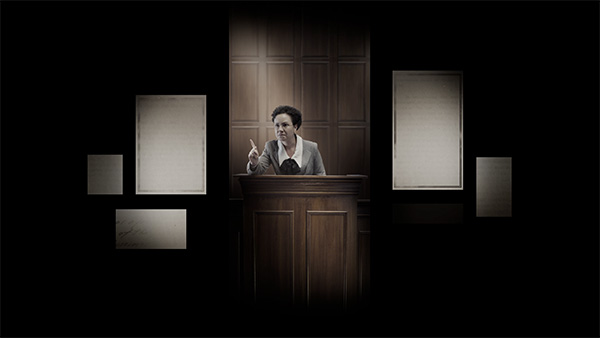 Film still of a white woman in WWI-era hair and dress gesturing angrily on the stand in a CGI rendering of a courtroom