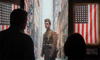 Photograph of museum guests watching a video of a person dressed as a WWI soldier