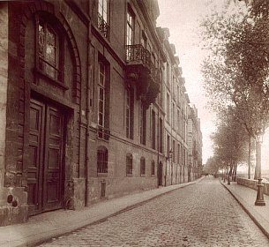 Sepia photograph of a Parisian city block. Brick building façades stretch away into the distance.