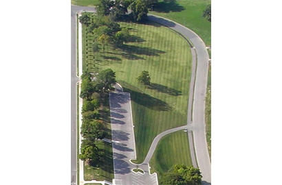 Top-down aerial view of a lawn expanse with a parking lot in the center