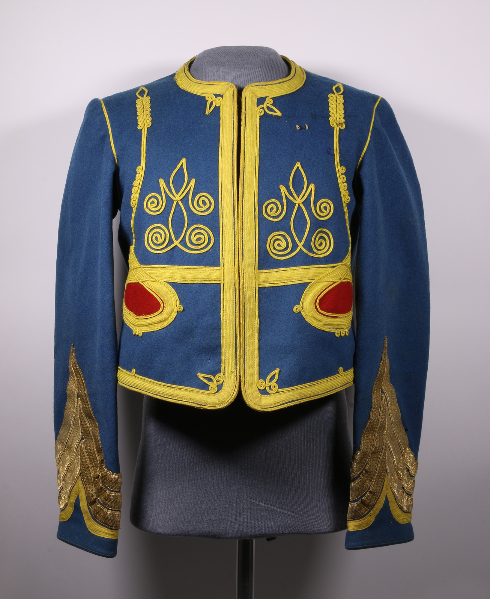 Modern photograph of a bright blue uniform tunic embroidered with bright yellow and red designs