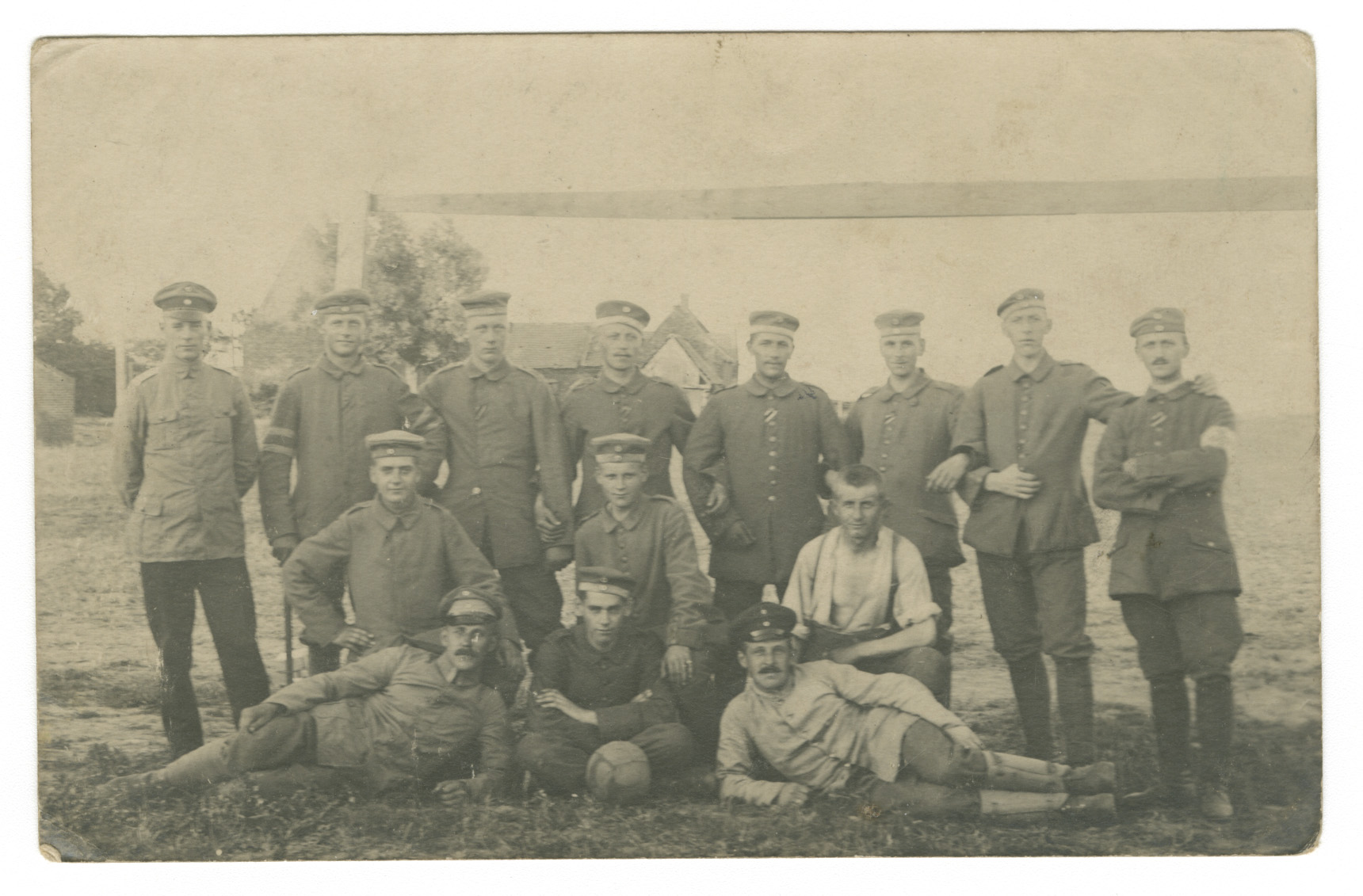 Black and white photo of a group of German soldiers in different WWI uniforms, posed standing, sitting and lying down along with a football/soccer ball.