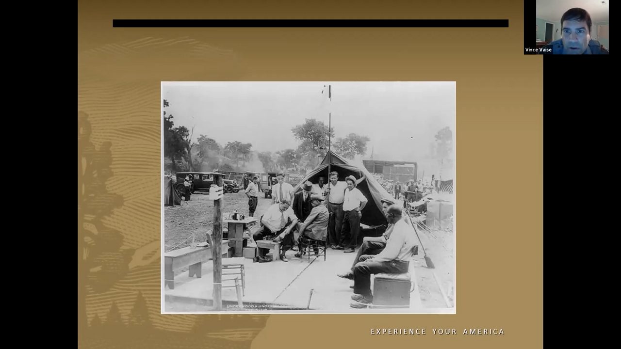 Photographie en noir et blanc d'un groupe d'hommes rassemblés devant une tente
