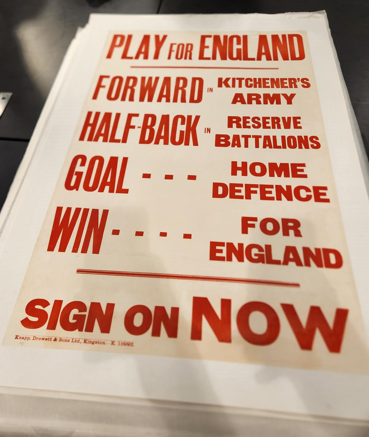 WWI poster consisting of red text on a cream background: "Play for England / Forward - Kitchener's Army / Half-back - Reserve Battalions / Goal - Home Defence / Win - For England / Sign on Now"