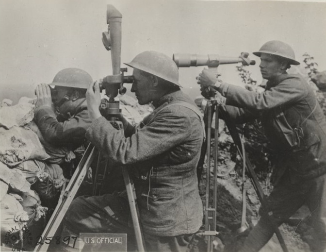 Black and white photo of three service members at an artillery observation post. The men aare each dressed in uniform and wearing helmets. One is using binoculars, another is using a trench periscope, and the third is using a type of telescope.