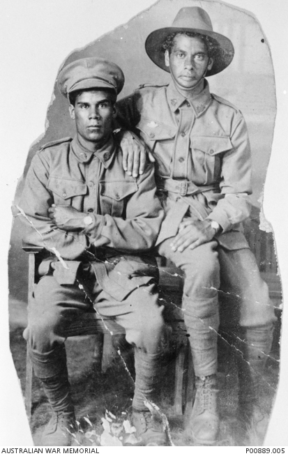 Black and white photo of two young brown-skinned men in Australian WWI military uniform, posed for a seated portrait
