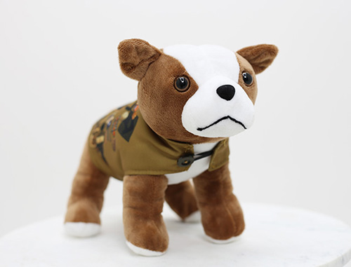 Modern photo of a brown dog plush wearing a jacket with patches on it