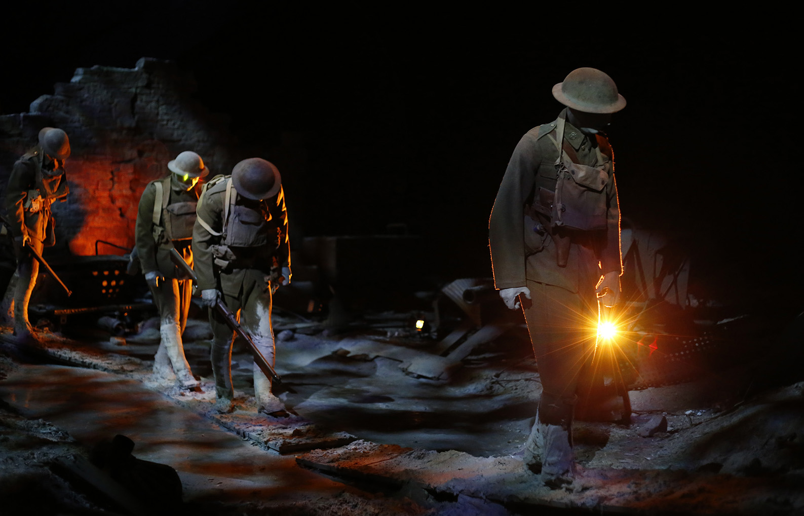 Life-size models of WWI soldiers trudge across a destroyed diorama landscape