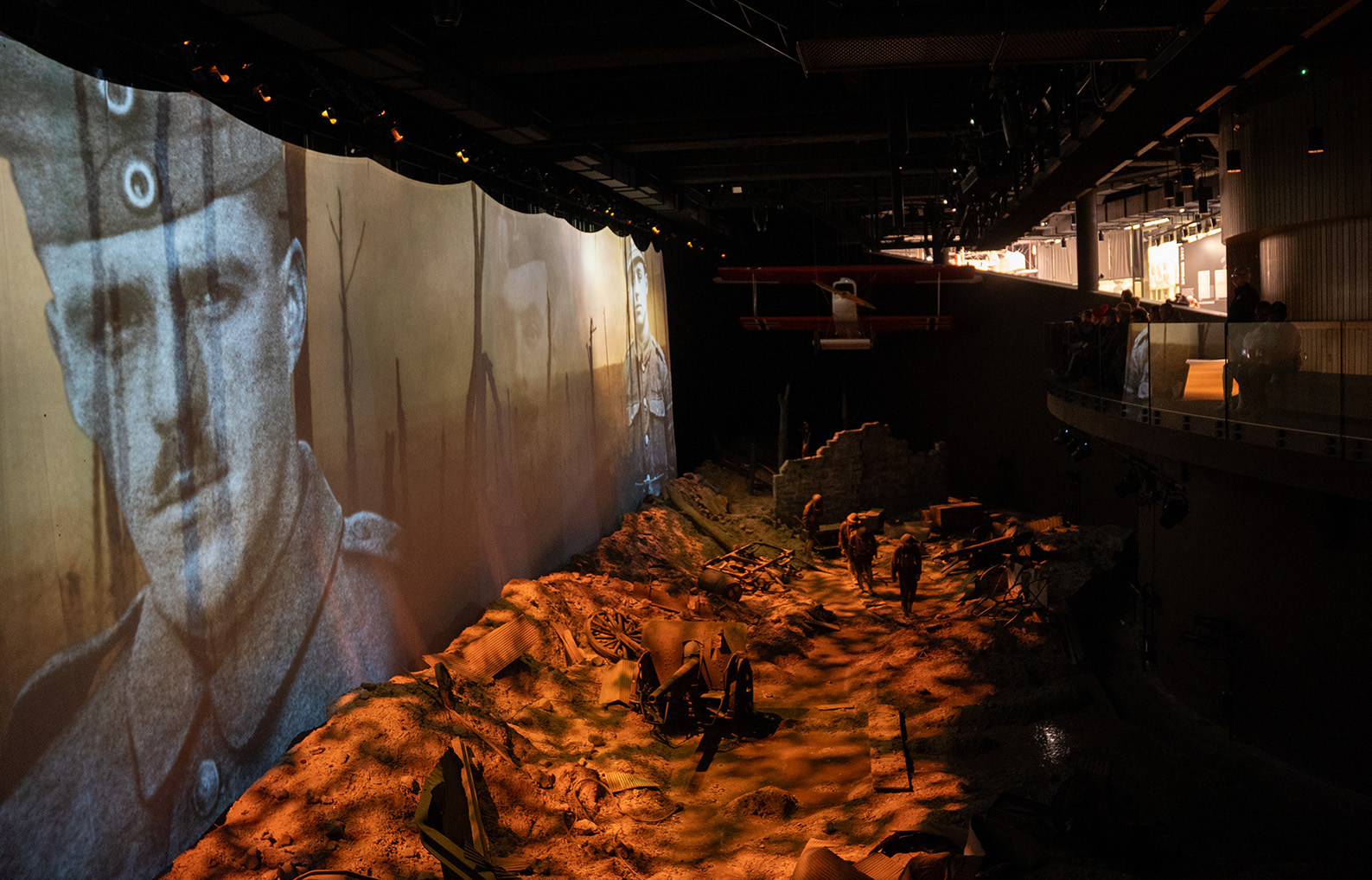 Museum guests watch a large video projected onto a screen over a battlescape diorama