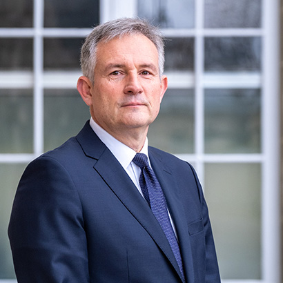 رجل أبيض مسن ذو شعر رمادي قصير يرتدي بدلة زرقاء داكنة