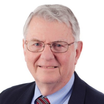 رجل أبيض مسن ذو شعر أبيض يرتدي نظارة وبدلة سوداء