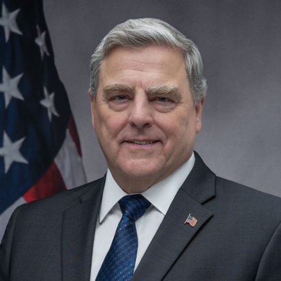 رجل أبيض مسن ذو شعر وحاجبين أبيضين يرتدي بدلة رمادية داكنة