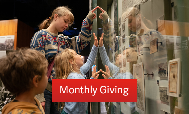 Two white girls point excitedly at artifacts in a glass exhibit case