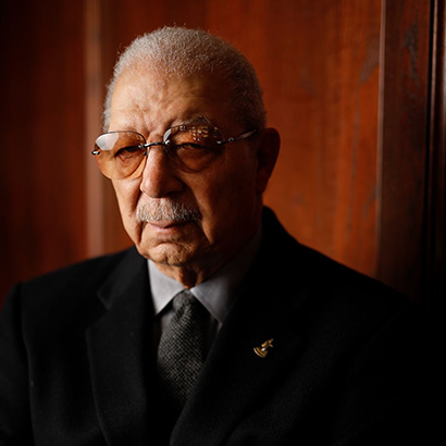 Photo of an older Black man wearing glasses and a black suit jacket