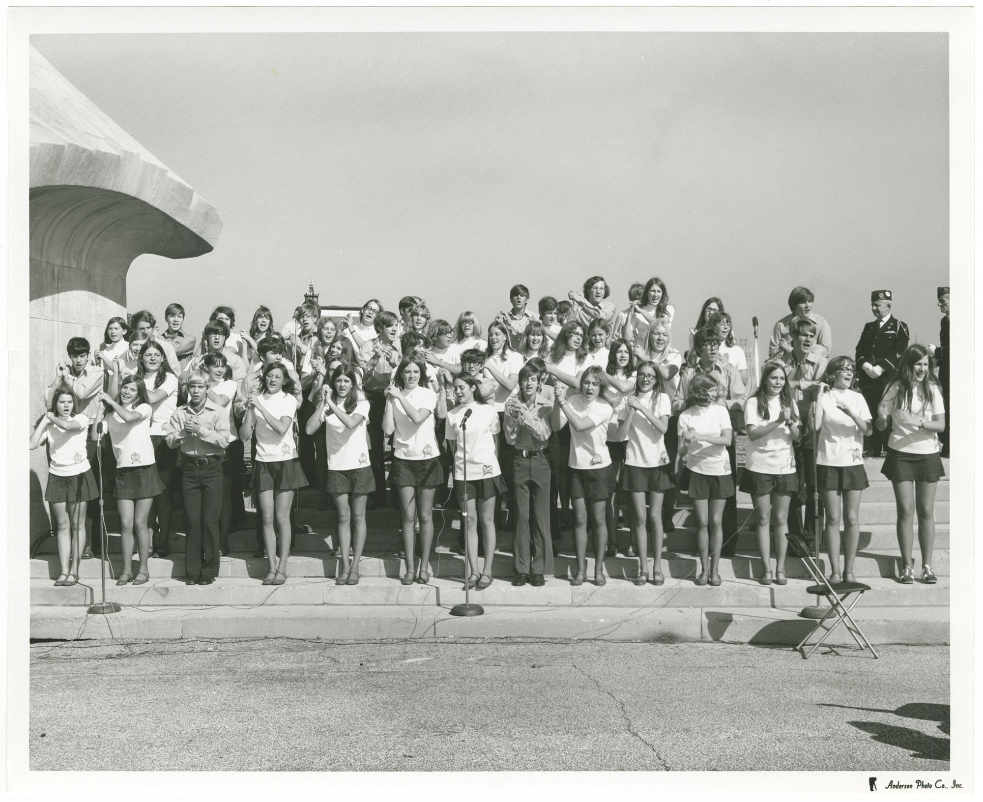 Black and white photograph of children standing in several rows singing on Memorial Courtyard