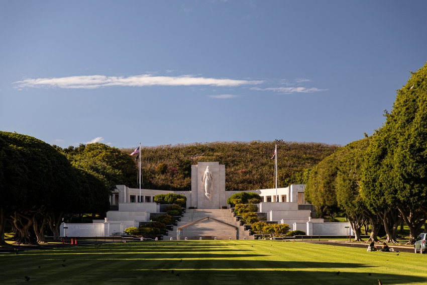 Color photograph of a large memorial building surrounded by trees and a grassy area.