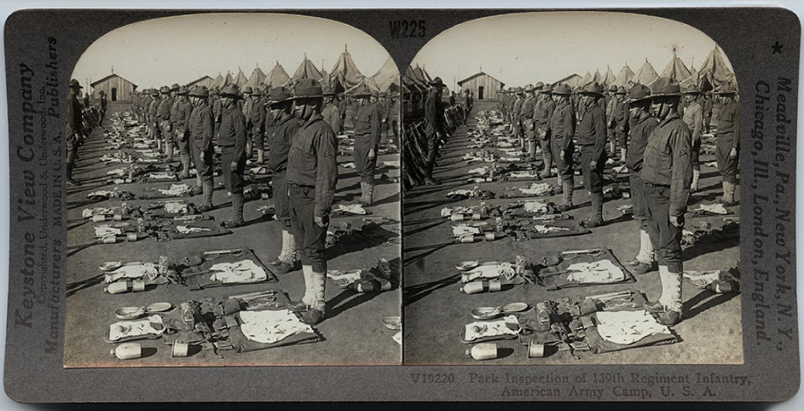Soldiers have their packs inspected at a field camp.