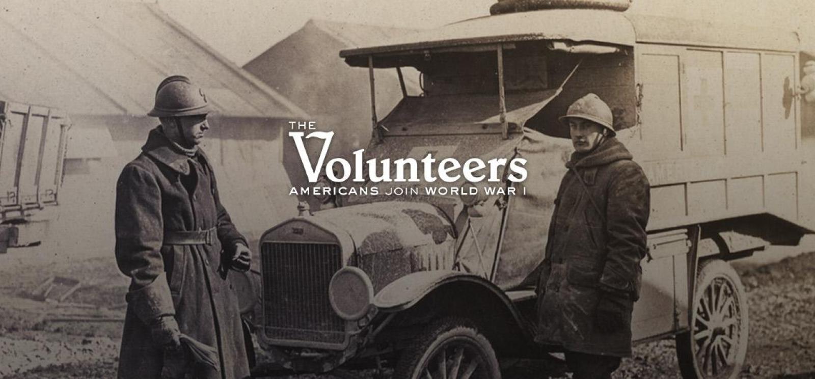 Image: two men dressed in thick overcoats and steel helmets stand next to a WWI-era truck. Text: The Volunteers. Americans Join World War I.