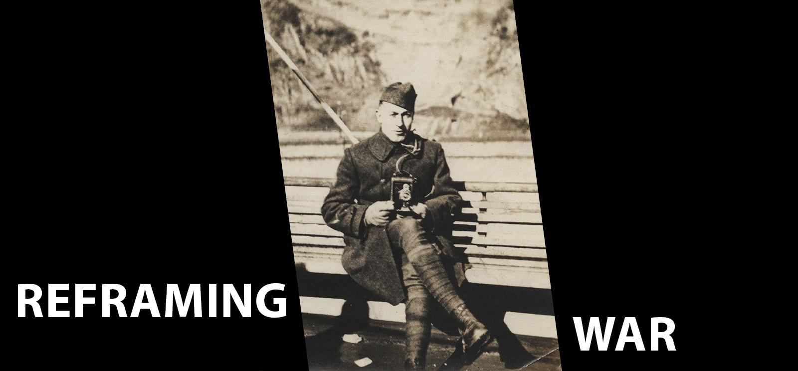 Image: Black and white photograph of a man in military uniform sitting down on a bench. He holds a WWI-era personal camera in his lap, aimed at the viewer. Text: Reframing War
