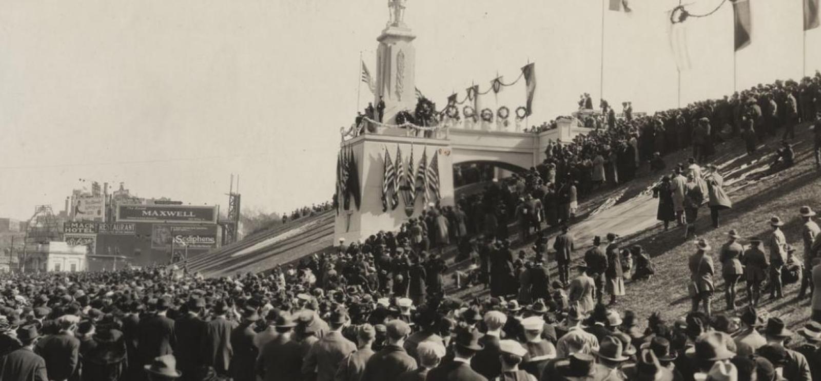 Black and white photograph of Liberty Memorial hill, crowned by a platform for speakers and flags. The hill is covered in spectators.