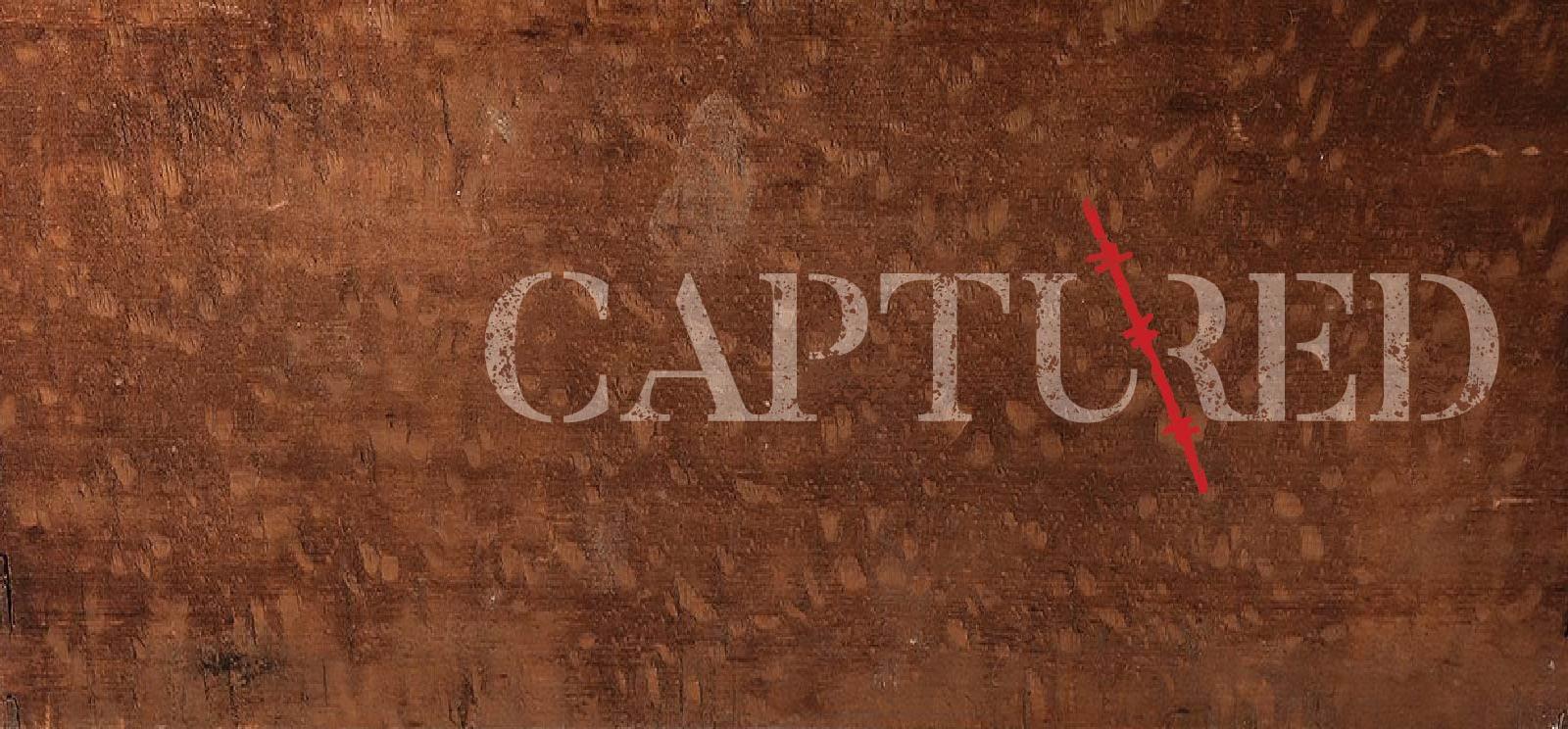 Text: 'Captured' in distressed typewriter font on wood background with a red barbed wire slash through the middle