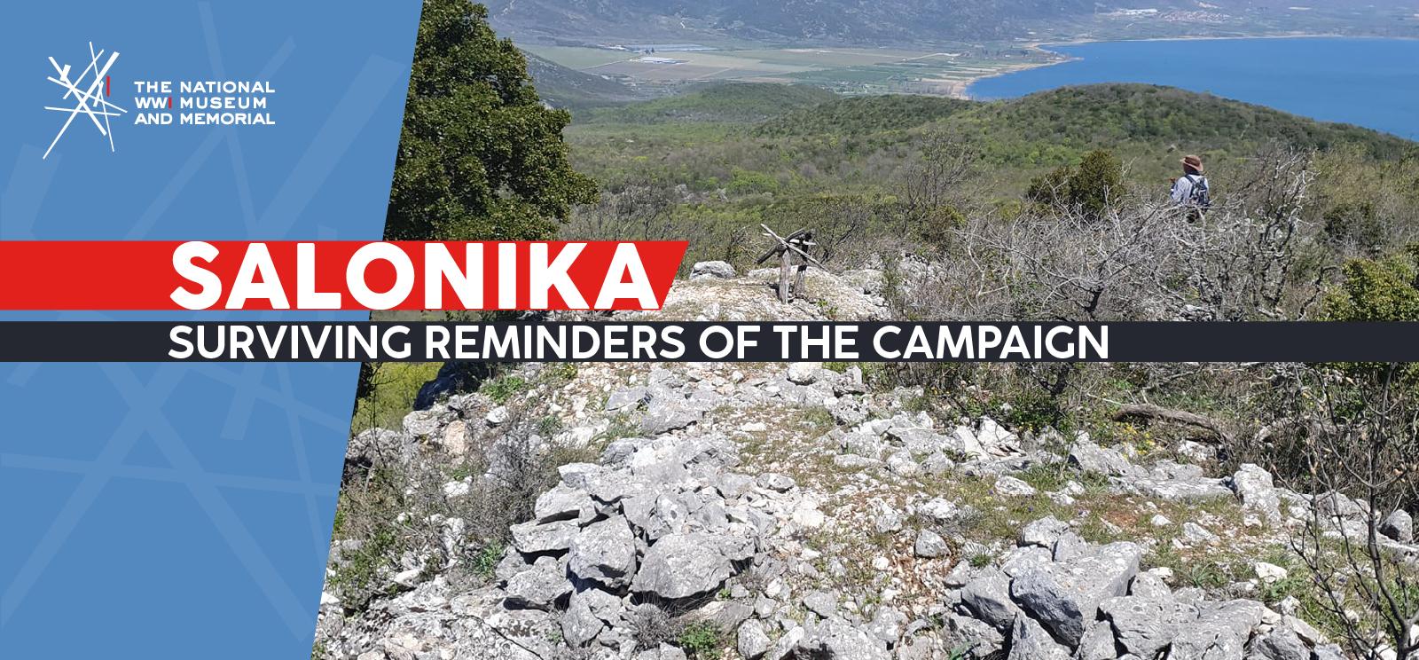 Image: modern color photograph on a rocky, scrubby hill overlooking a valley with a very blue lake. A small wooden structure is resting on the crest of the hill. People's hats and heads are just visible in the scrub brush beyond. Text: 'Salonika / Surviving Reminders of the Campaign'