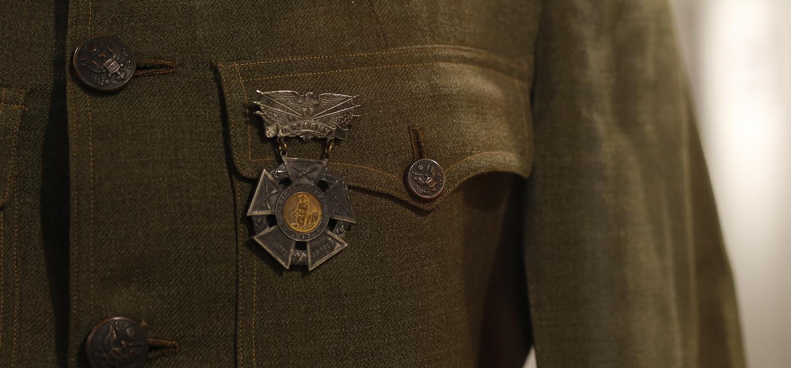 Close-up detail shot on an olive-colored uniform tunic and a medal hanging from the chest pocket