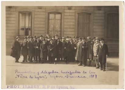 Sepia photo of a group of men and women in overcoats and hats looking at the camera
