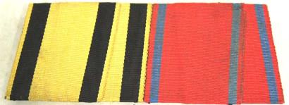 Photograph of two folded ribbons. The one on the left is yellow with black stripes. The one on the right is red with blue stripes.