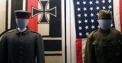 Photographie de deux uniformes militaires sous les drapeaux allemand et américain