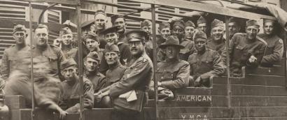 Photo en noir et blanc d'un grand groupe d'hommes en uniforme militaire assis dans un bus touristique dans une ville française.