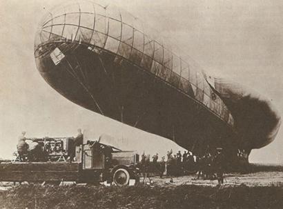 Sepia photograph of a sausage-shaped dirigible tethered to the ground