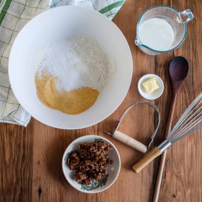 Photograph from above of bowl of flour and cornmeal, surrounded by baking equipment