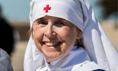 Modern photograph of an smiling older white woman dressed in a nurse's Red Cross uniform from WWI.