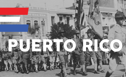Black and white photograph of soldiers marching down a street. Text: 'Puerto Rico'