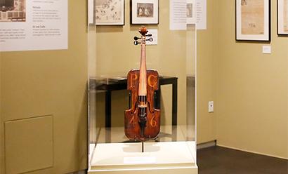 Modern photograph of a handmade violin in a clear exhibit case