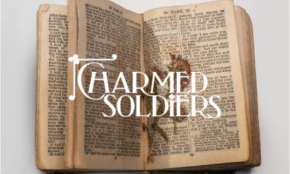 Modern photograph of a WWI-era Bible open to display pressed flowers between the pages. Text in white: 'Charmed Soldiers'