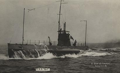 Black and white photograph of a WWI submarine surfacing from the sea.