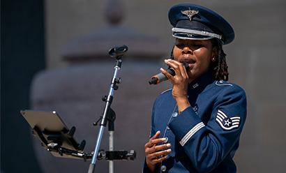 Modern photograph of a Black woman in military uniform singing into a microphone