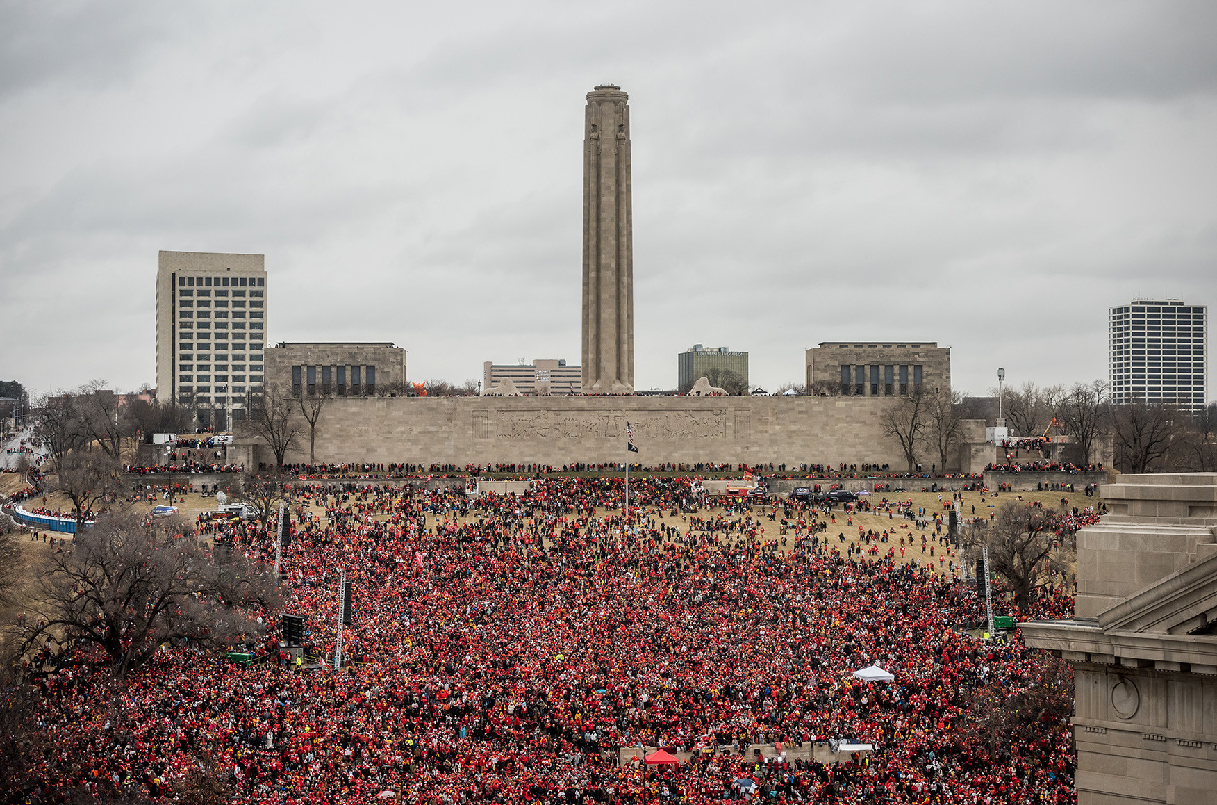 Photographie moderne de la pelouse nord du musée et du mémorial avec la Liberty Memorial Tower en arrière-plan. Toute la zone est remplie d'une foule immense vêtue de rouge.