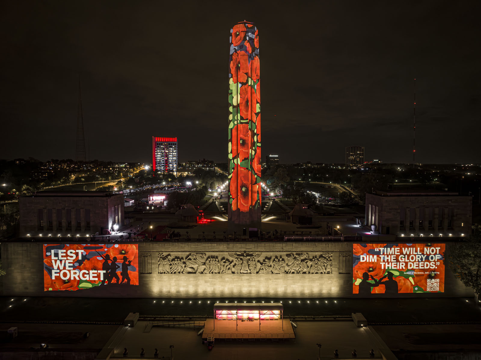 Photographie moderne de la Liberty Memorial Tower, de la grande frise et du mur de la terrasse nord prise d'en haut au-dessus de la pelouse nord. La Tour est couverte de projections de coquelicots. Plus de coquelicots ainsi que du texte et des images sont projetés sur le mur de la terrasse nord de chaque côté de la grande frise.
