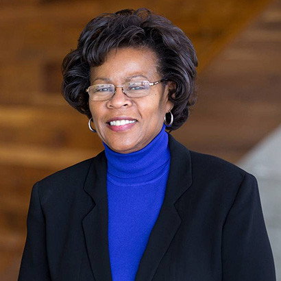 Middle-aged Black woman with fluffy bobbed hair wearing a blue turtleneck and dark blazer
