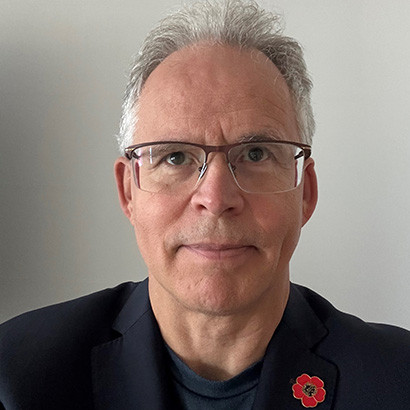 Modern photo of an older white man wearing glasses and a poppy pin