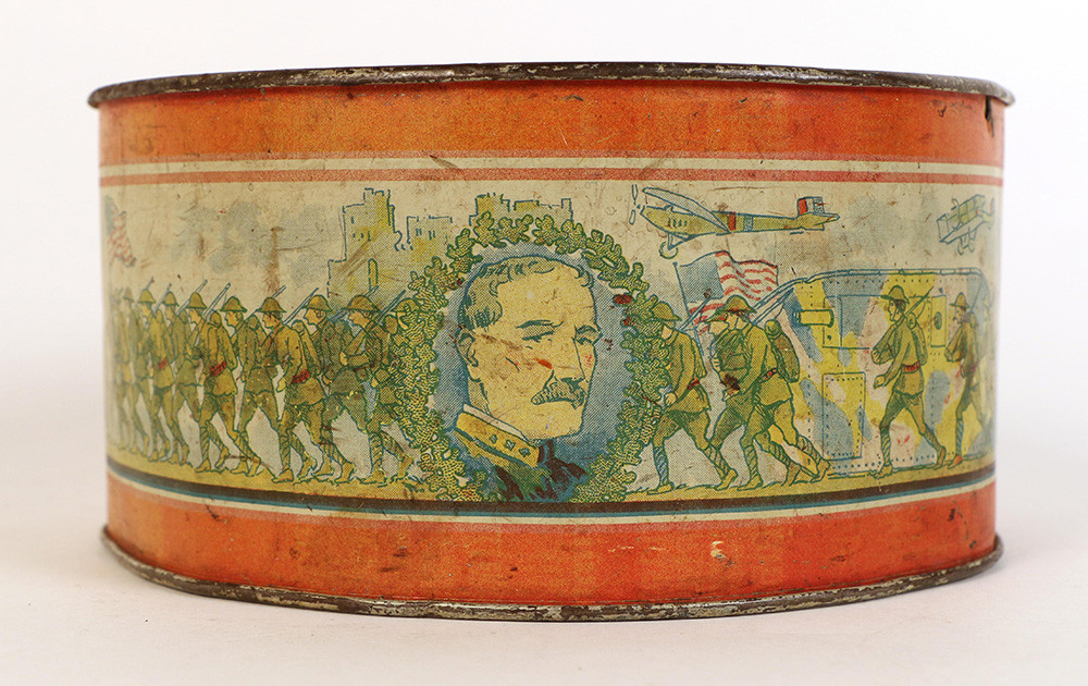 Side view of a toy drum decorated with a portrait of a white man with a mustache and images of WWI doughboys marching.