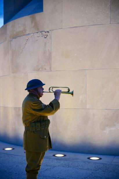 Bugler in WWI-era uniform in profile in front of the Liberty Memorial Tower